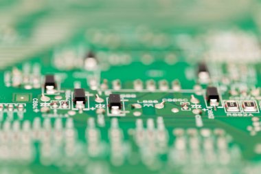 Macro close-up of surface-mount transistors on a green printed circuit board, showing electronic components with detailed soldering and layout.
