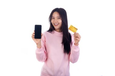 Elinde akıllı telefon ve kredi kartı olan gülümseyen kadın dijital ödeme ve online alışveriş kavramları sunuyor, beyaz arka planda izole edilmiş.