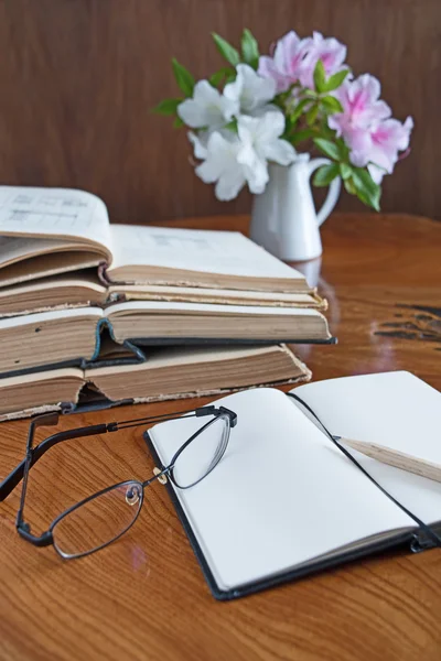 Pilha de livros em uma mesa de madeira com óculos — Fotografia de Stock