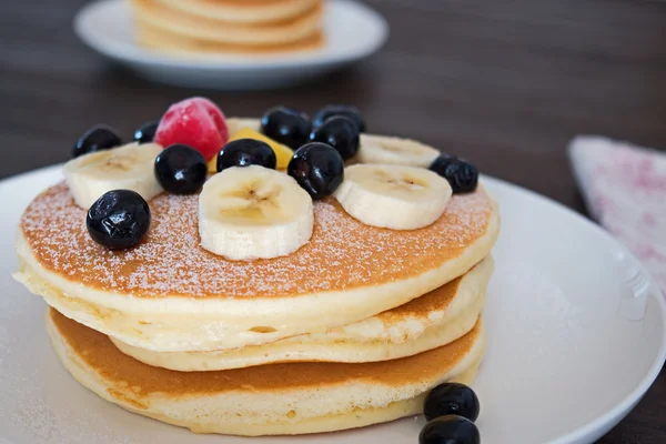 Panqueques con arándanos y plátanos en plato blanco — Foto de Stock