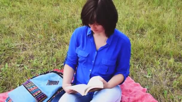 Menina com um livro ao ar livre no verão — Vídeo de Stock