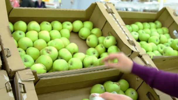 Женщина выбирает зеленые яблоки в продуктовом — стоковое видео
