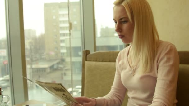 Girl in cafe with menu and cellphone — Stock Video