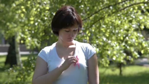 Woman pinning pink breast cancer awareness ribbon — 图库视频影像