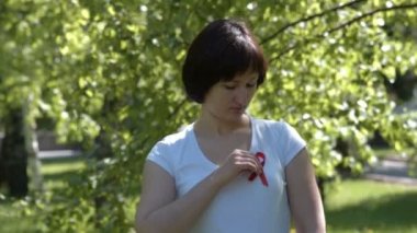 Woman pinning red awareness ribbon