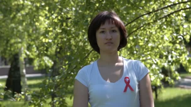 Young woman with red awareness ribbon — Stockvideo