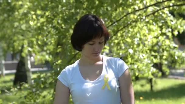 Женщина прикрепляет желтую ленту осознания — стоковое видео