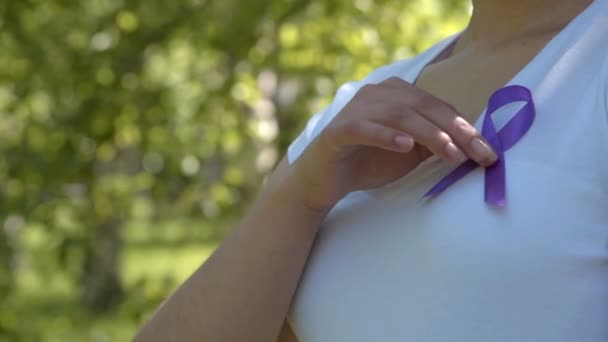 Mädchen pinnt lila Bewusstseinsband auf weißes T-Shirt — Stockvideo