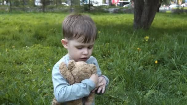 Child with toy bear friend in the park — Stock Video