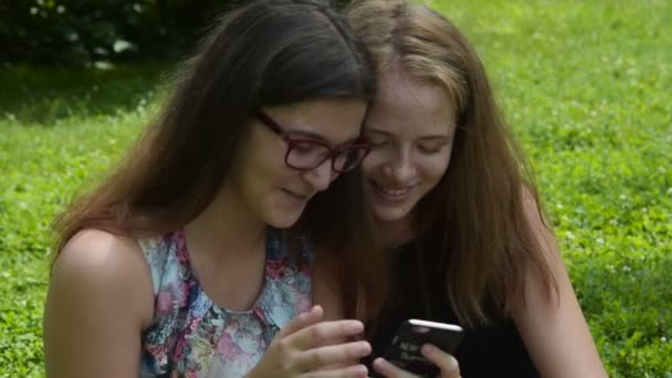 Две девушки смеются при использовании мобильного телефона — стоковое видео