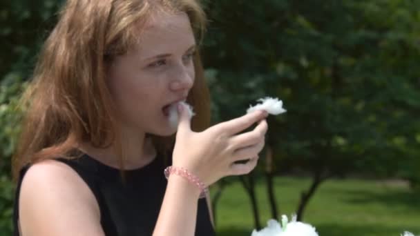 Дівчина-підліток їсть бавовняні цукерки на відкритому повітрі — стокове відео