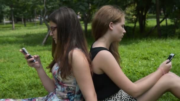 Chicas adolescentes con teléfonos celulares en el parque — Vídeos de Stock