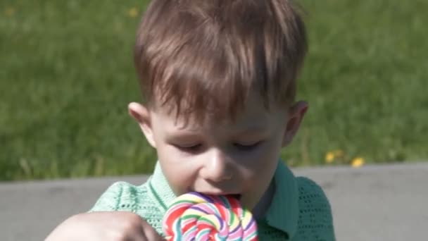 Kind met lollipop in het park — Stockvideo