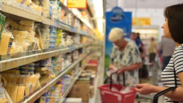 Mensen winkelen in de zuivel afdeling van de supermarkt — Stockvideo