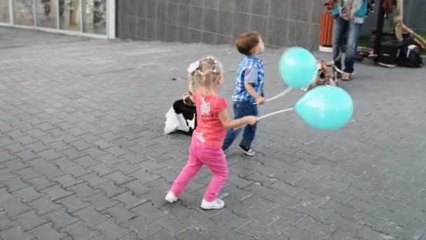 Chłopiec i dziewczynka z balonami grając na ulicy — Wideo stockowe