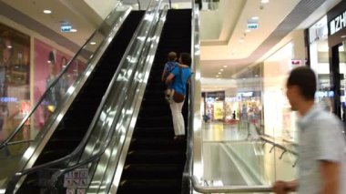 Ticaret merkezinde yürüyen merdivene binen insanlar