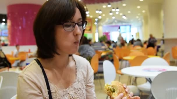 Žena jíst hamburger v kavárně shopping mall — Stock video