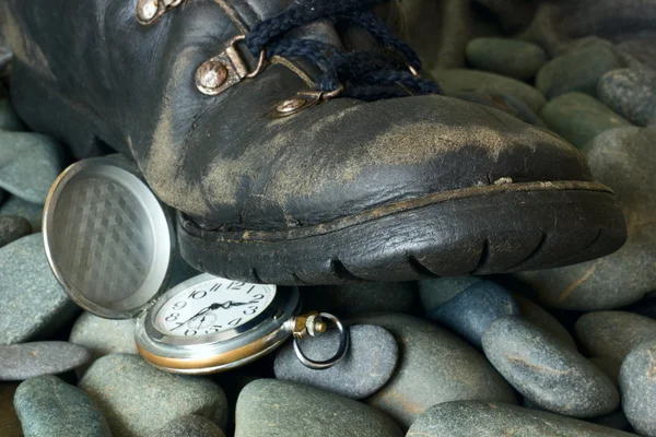 El pie en una bota pisa el reloj . —  Fotos de Stock