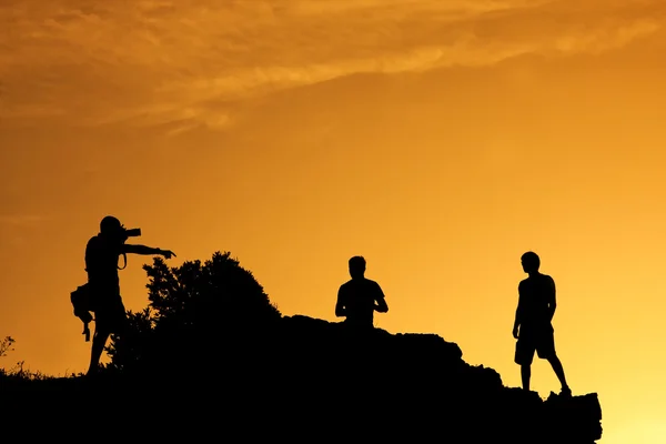 Silhouettes of a photographer and his models in sunset