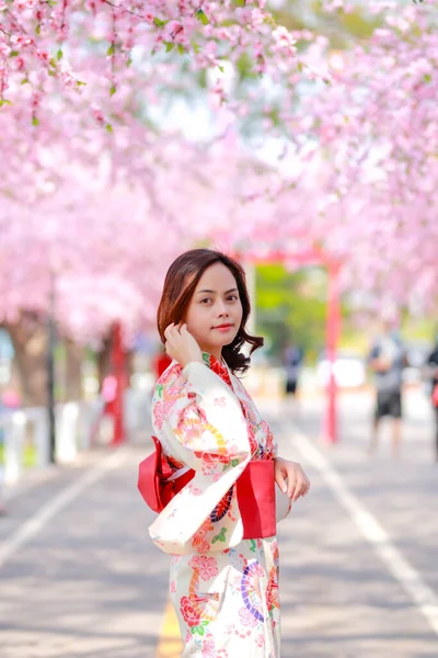 日本樱花园 一位年轻的亚洲女子身穿婚纱 下午日光浴时走在树上的画像 — 图库照片