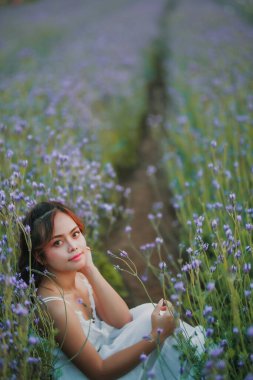 Lavanta tarlasında uzun sarı saçlı bir kadın. Stil hayatı, yaz günlerinde uzun beyaz elbiseli ve rahatlamış bir şekilde seyahatin tadını çıkarır..
