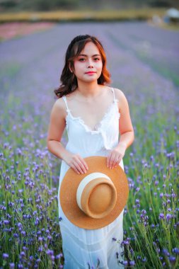 Lavanta tarlasında uzun sarı saçlı bir kadın. Stil hayatı, yaz günlerinde uzun beyaz elbiseli ve rahatlamış bir şekilde seyahatin tadını çıkarır..