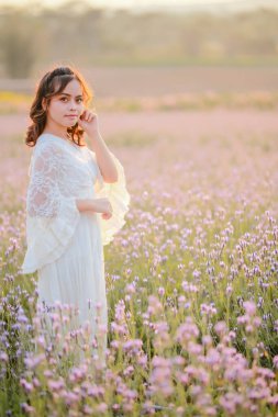 Lavanta tarlasında uzun sarı saçlı bir kadın. Stil hayatı, yaz günlerinde uzun beyaz elbiseli ve rahatlamış bir şekilde seyahatin tadını çıkarır..