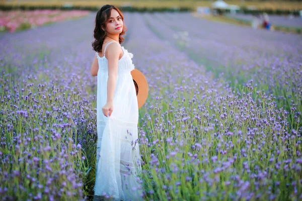 Blond long haired woman in lavender field. Style life enjoying journey to travel on vacation with relaxation with in long white dress outdoors on summer day.