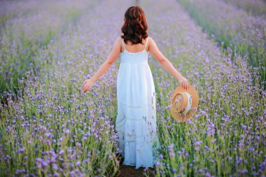 Lavanta tarlasında uzun sarı saçlı bir kadın. Stil hayatı, yaz günlerinde uzun beyaz elbiseli ve rahatlamış bir şekilde seyahatin tadını çıkarır..