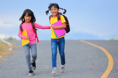 Covid-19 salgınından sonra okula geri döndü. İki küçük tatlı kız okula giderken kollarında kitap tutarak ve çantalarını çantasıyla yürüyüp konuşuyorlardı..