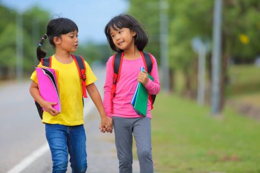 Covid-19 salgınından sonra okula geri döndü. İki küçük tatlı kız okula giderken kollarında kitap tutarak ve çantalarını çantasıyla yürüyüp konuşuyorlardı..