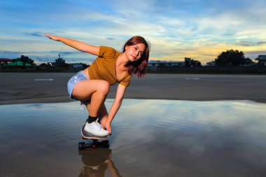 Asyalı kadınlar güzel bir yaz gününde dışarıda sörf ya da paten oynuyorlar. Spor aktivitesi yaşam tarzı konsepti, sağlıklı ve egzersiz.