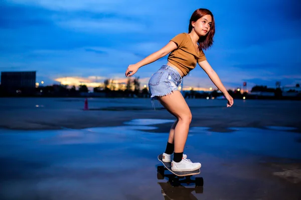 Asian women playing surf skate or skates board outdoors on beautiful summer day. Sport activity lifestyle concept, Healthy and exercise.