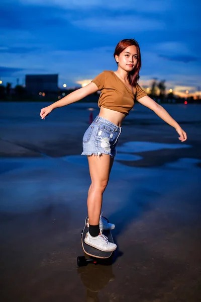 Asian women playing surf skate or skates board outdoors on beautiful summer day. Sport activity lifestyle concept, Healthy and exercise.