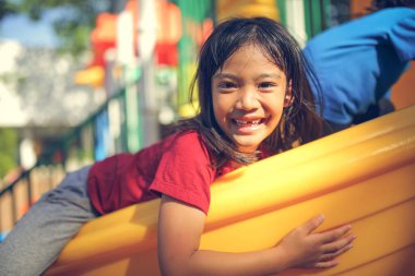Neşeli, neşeli küçük kız yaz aylarında oyun parkında dolaşır. Açık hava aktivitesi. İnandırıcılık ve dış eğitim konsepti..