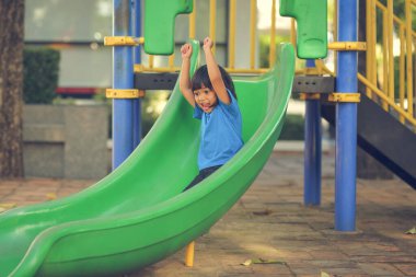 Neşeli, neşeli küçük kız yaz aylarında oyun parkında dolaşır. Açık hava aktivitesi. İnandırıcılık ve dış eğitim konsepti..