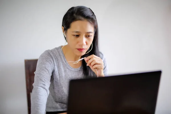 Girl student study online with  teacher using notebook, happy young woman learn language listen lecture watch webinar write notes look at laptop sitting in her room,distant education.