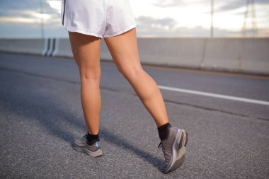 Genç fitness Asyalı kadın siyah gömlek ve beyaz şort giyiyor. Yaşam tarzı sağlığı için şehir yolunda koşuyor ve koşuyor..