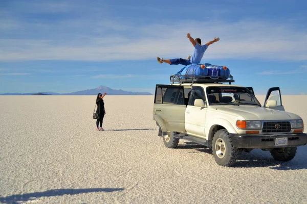 Les touristes posent sur une jeep dans le désert salé bolivien Uyuni — Photo