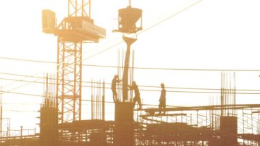 İnşaat alanında çalışan işçilerin siluetlerinin görüntüleri.