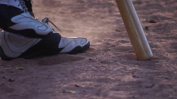 暖かい光の中で野球選手の足と地面でのバットのクローズアップ映像 — ストック動画