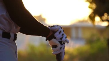 Beyzbol oyuncusunun gün batımında beyzbol sopasıyla sahada yavaş çekim görüntüsü. 