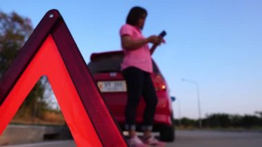 footage of woman calling phone help because her car is broken down, red car on the road and woman asking for help insurance officers