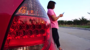 footage of woman calling phone help because her car is broken down, red car on the road and woman asking for help insurance officers