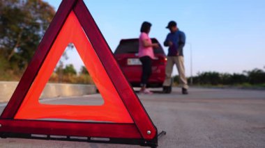 footage of woman calling phone help because her car is broken down, red car on the road and woman asking for help insurance officers