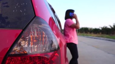 footage of woman calling phone help because her car is broken down, red car on the road and woman asking for help insurance officers