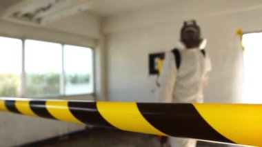 Korunma kostümü, solunum cihazı ve dezenfekte aparatıyla boş bir binada yürüyen ve Coronavirus 'a karşı kimyasal dezenfeksiyon yapan adam.