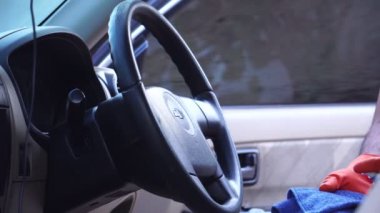 Lastik eldivenli bir adamın dezenfekte ettiği, direksiyon simidini sildiği görüntüler.