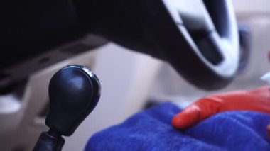 Lastik eldivenli bir adamın araba teçhizat panelinin yüzeyini dezenfekte ederken görüntüsü.