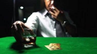 Sigara içen, viski içen ve kumarhanede poker oynayan bir adam. Risk oyunu kavramı, masada poker fişleri